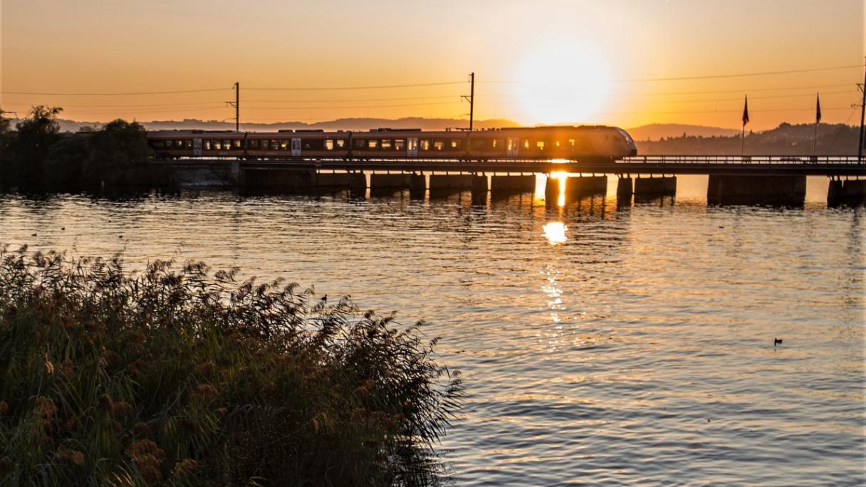 SOB Herbsthit: Voralpenexpress auf dem Holzsteg bei Rapperswil bei Sonnenuntergang.