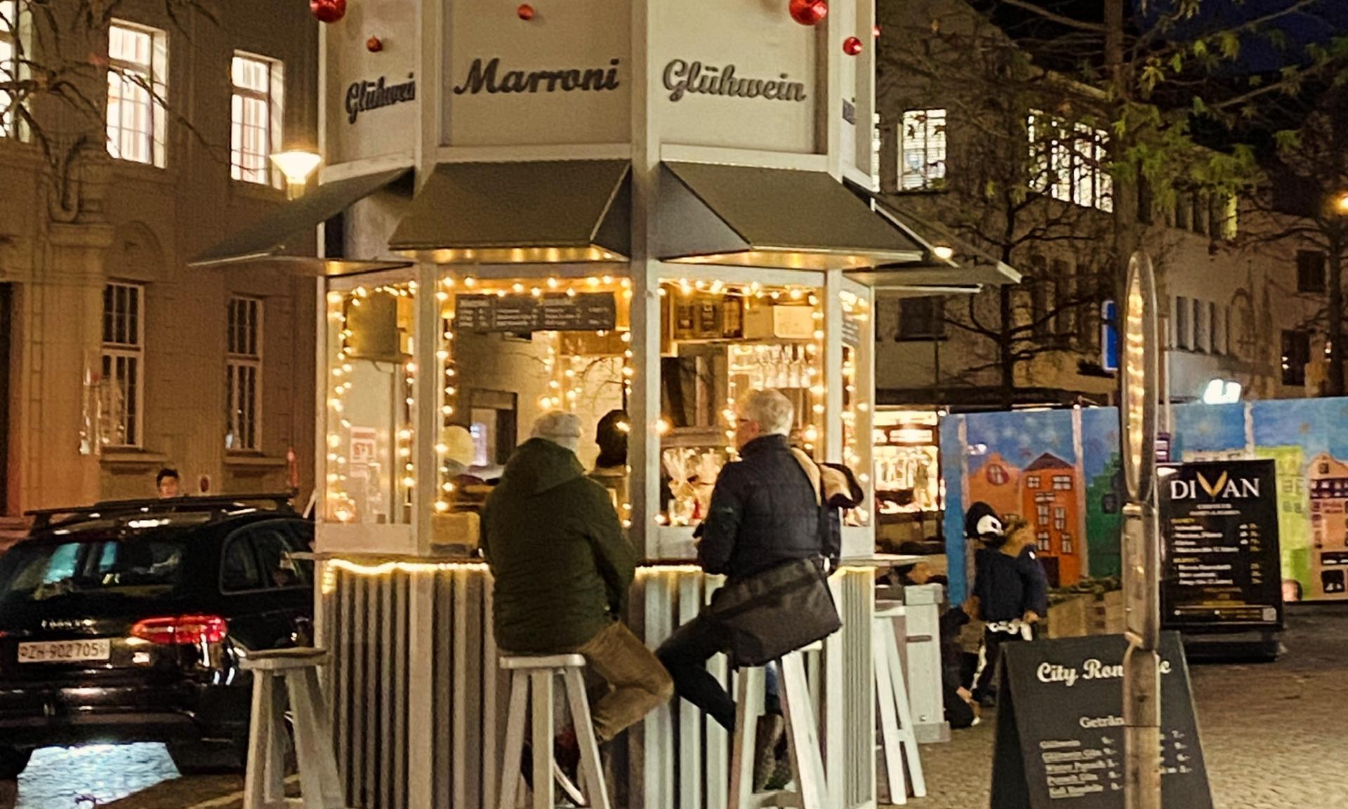 Gäste mit Glühweintassen im Gespräch an der rundum offenen Bartheke der City Rondelle